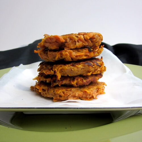 A stack of five sweet potato fritters on a white plate.