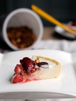 A slice of cheesecake with strawberry compote on a white plate