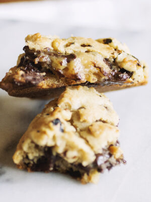 A chocolate chip Levain copycat cookie broken in half on a marble background.