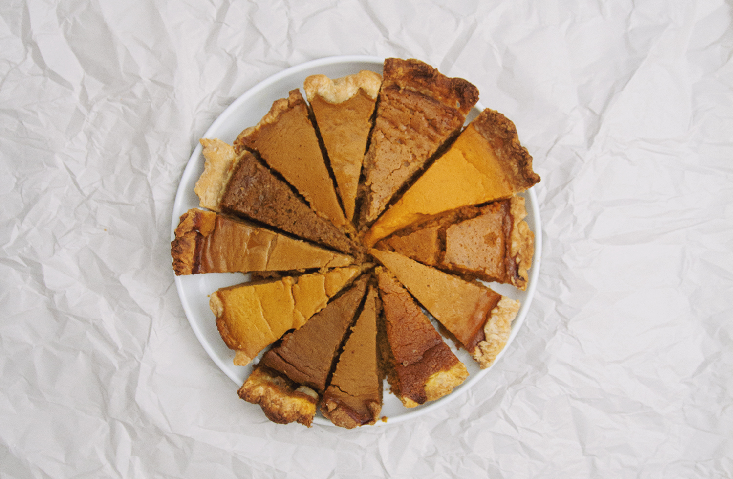 12 slices of different pumpkin pie recipes on white plate