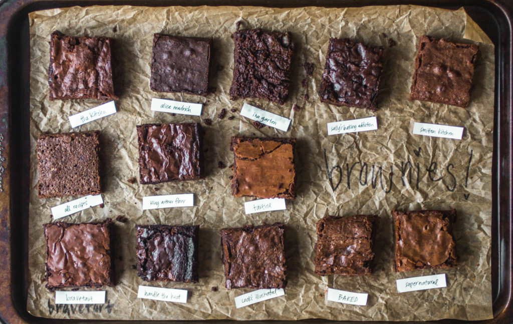 Close up on different squares of brownies on a parchment-lined baking sheet.