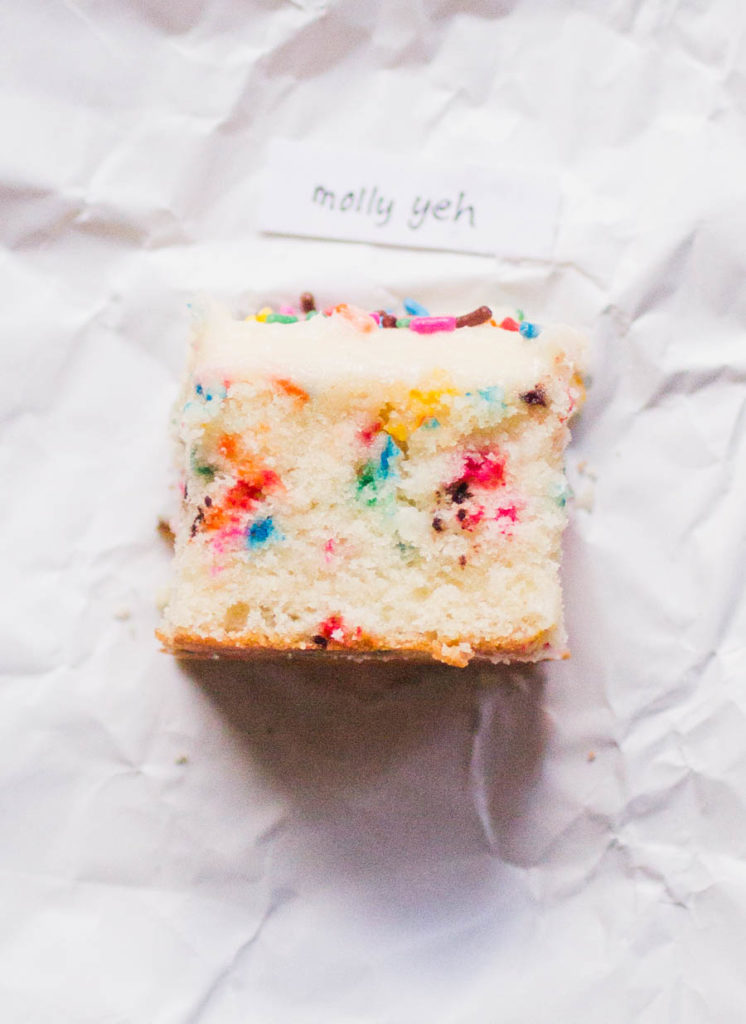 Single slice of Molly Yeh sprinkle cake recipe on white parchment paper