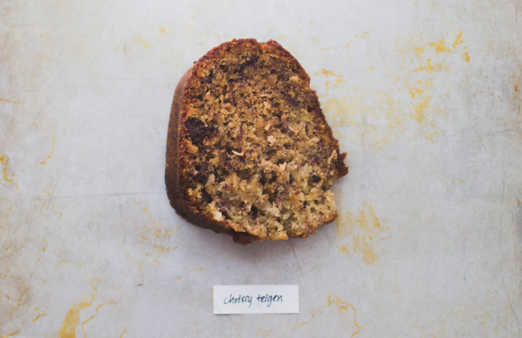 Round slice of rich chocolate and coconut studded banana bread on baking tray - Recipe by Chrissy Teigen
