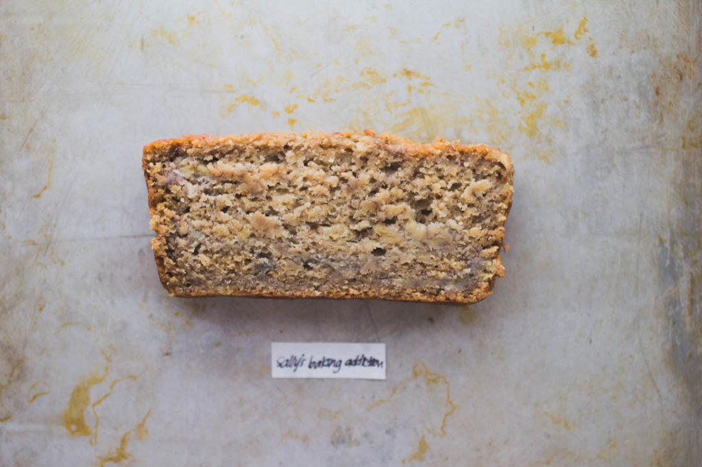 A slice of dense, moist lightly golden banana bread on baking tray - Recipe by Sally's Baking Addiction