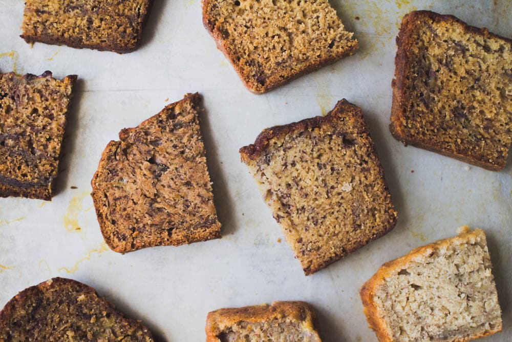9 slices of different recipes of banana bread cut in half and lined on a baking tray