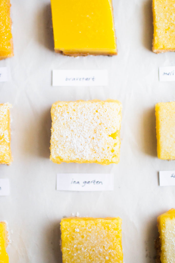Several slices of different lemon bar recipes on white parchment paper