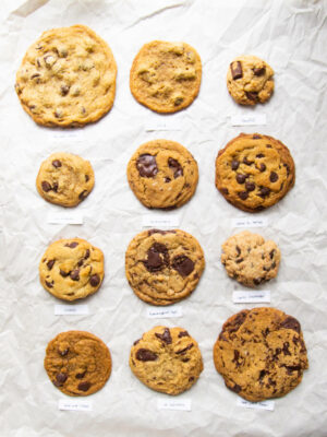 12 different vegan chocolate chip cookie recipes lined up on parchment paper