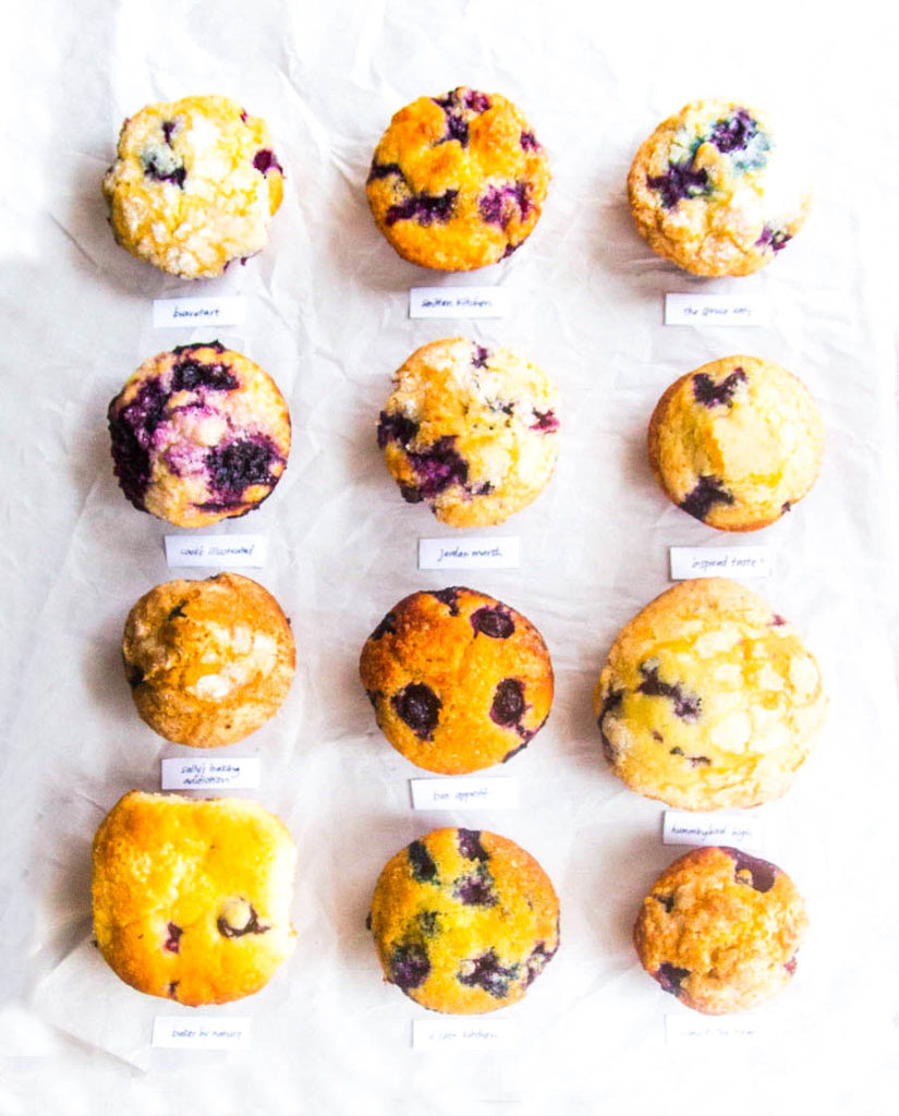 overhead view of 12 lined up blueberry muffins on white parchment paper