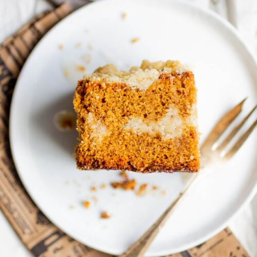 A slice of gingerbread coffee cake on a white plate with a fork.
