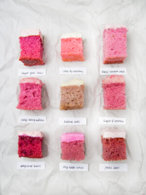 9 squares of different frosted strawberry cake on a crinkled white background