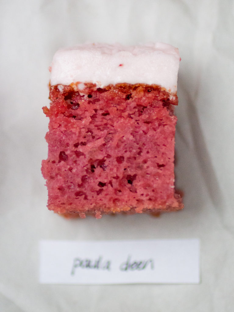 single slice of pink strawberry cake with light pink icing by Paula Deen on white parchment