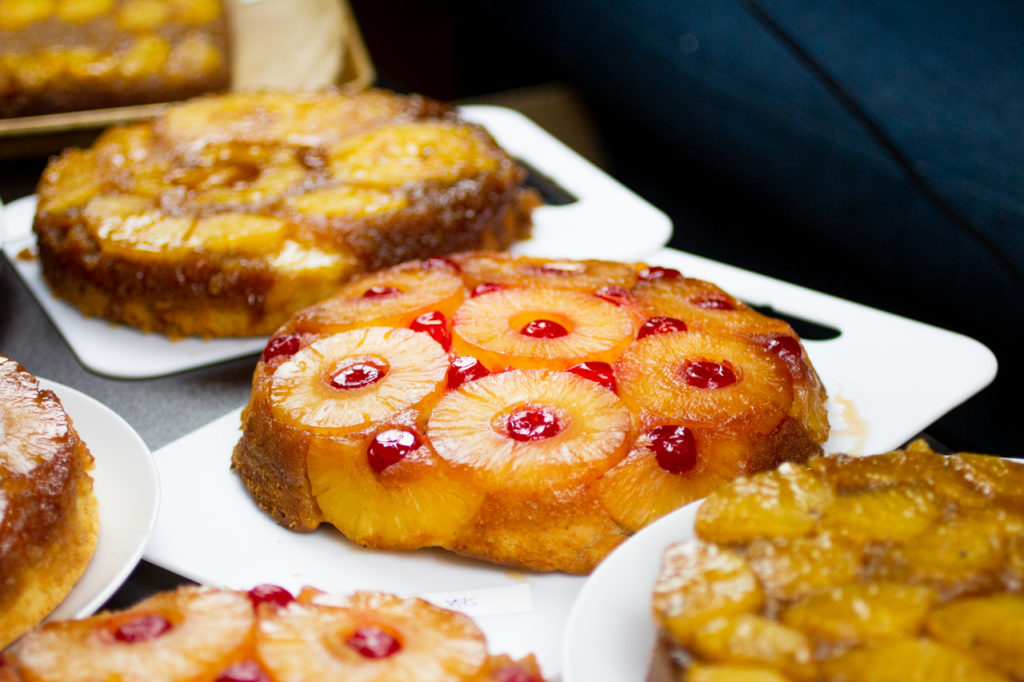 a pineapple upside cake on a white cutting board surrounded by other cakes