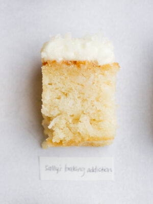 square of frosted coconut cake on a gray background with the label "sally's baking addiction."