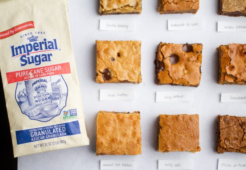 9 blondie squares on a gray background next to a bag of imperial sugar.