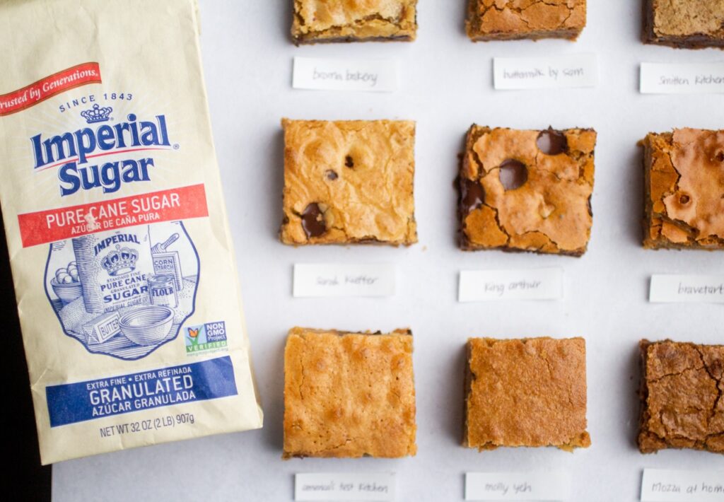 9 blondie squares on a gray background next to a bag of imperial sugar