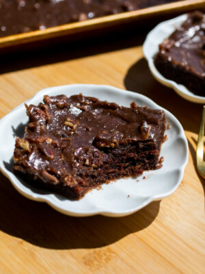 A slice of chocolate cake topped with chocolate frosting and pecans.