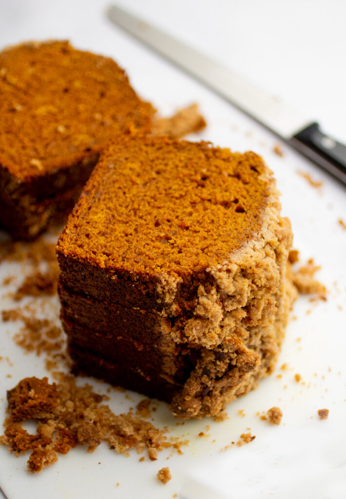 a stack of pumpkin bread slices with a streusel top on a white background