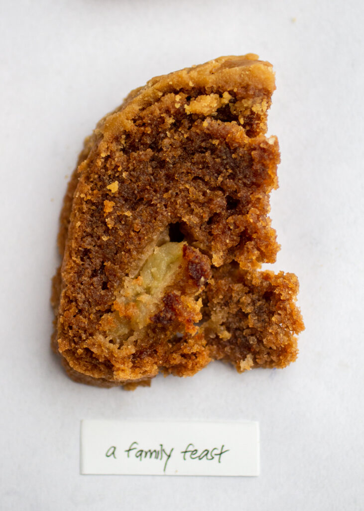 a slice of apple cake with the label \"a family feast\" on a gray background.