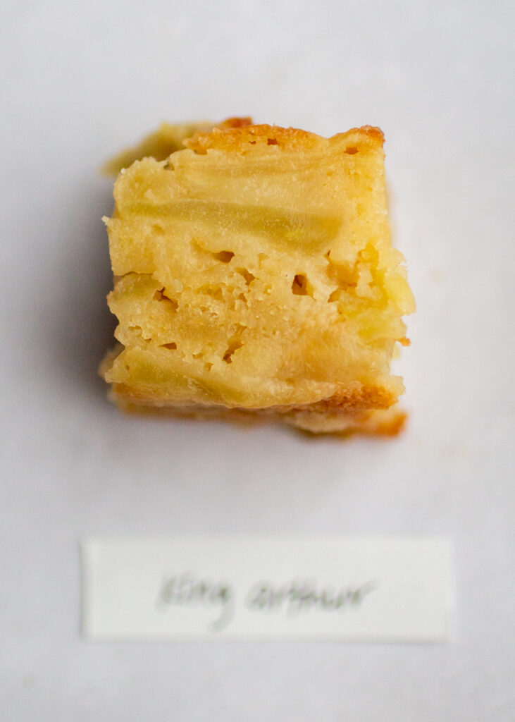 a slice of apple cake with the label \"king arthur\" on a gray background.