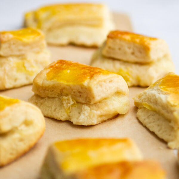 a bunch of cheese rolls on a piece of parchment against a gray background
