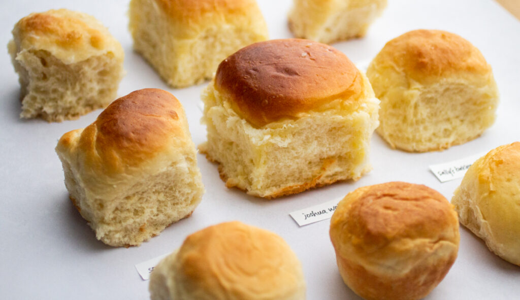 A close up of a fluffy dinner roll surrounded by other rolls.