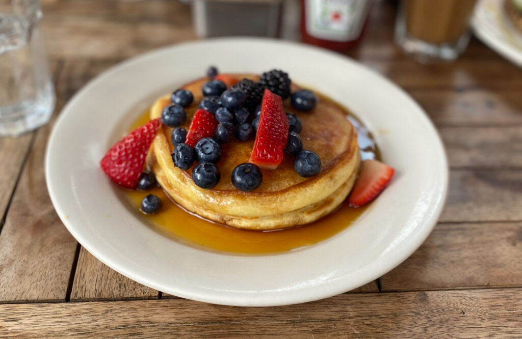 a stack of pancakes with berries and syrup from La Bergamote.