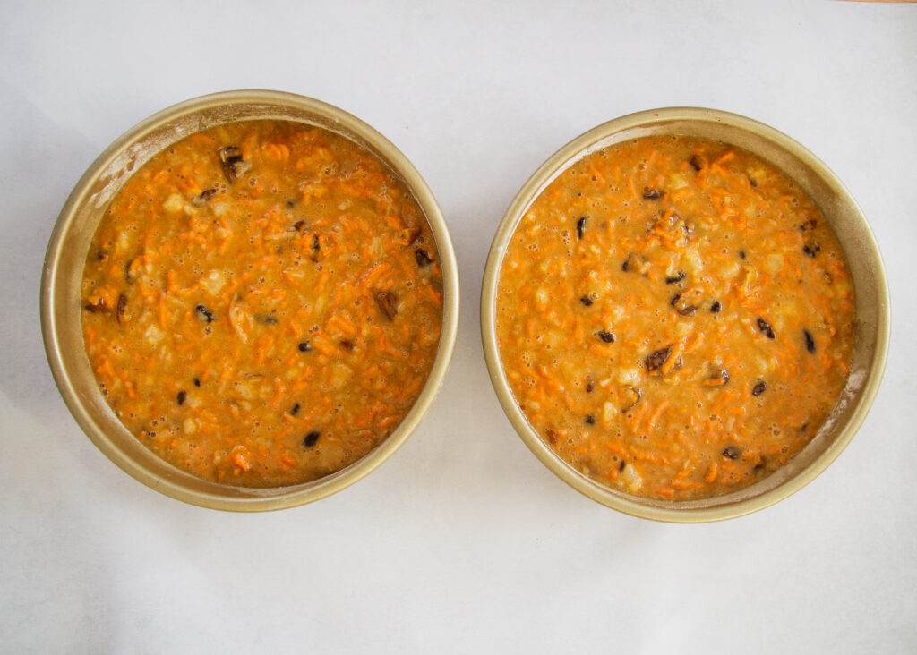 two cake pans filled with carrot cake batter.