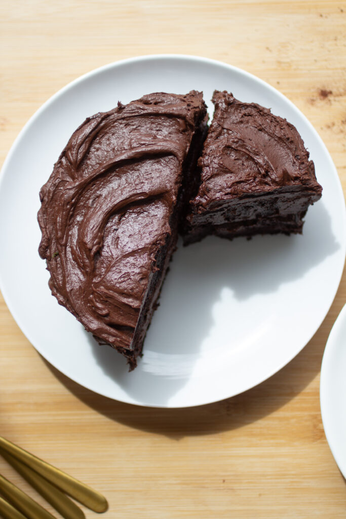 Half of a frosted chocolate cake on a white plate.