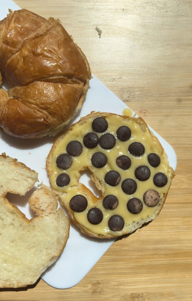 Croissant half topped with almond paste and chocolate chips.
