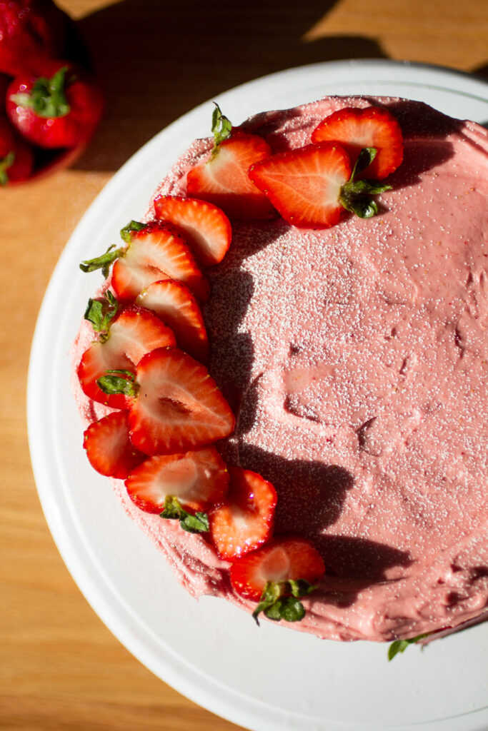 overhead view of a strawberry cake with sliced strawberries around the side.