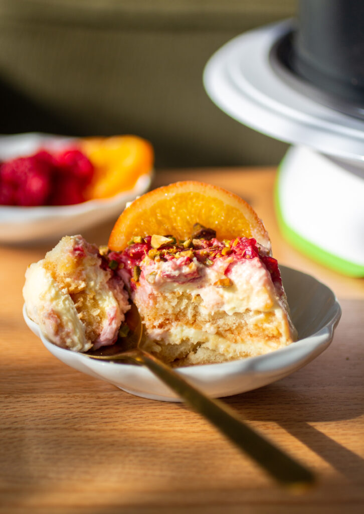A slice of blood orange raspberry tiramisu on a plate with a fork.