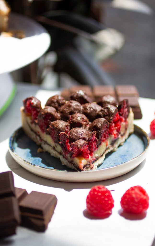 a slice of chocolate raspberry tart on a blue plate.