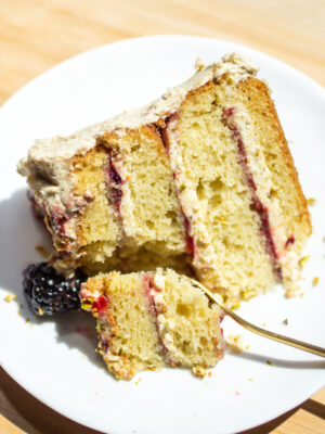 a slice of a four layer olive oil cake on a plate with a fork cutting a bite.