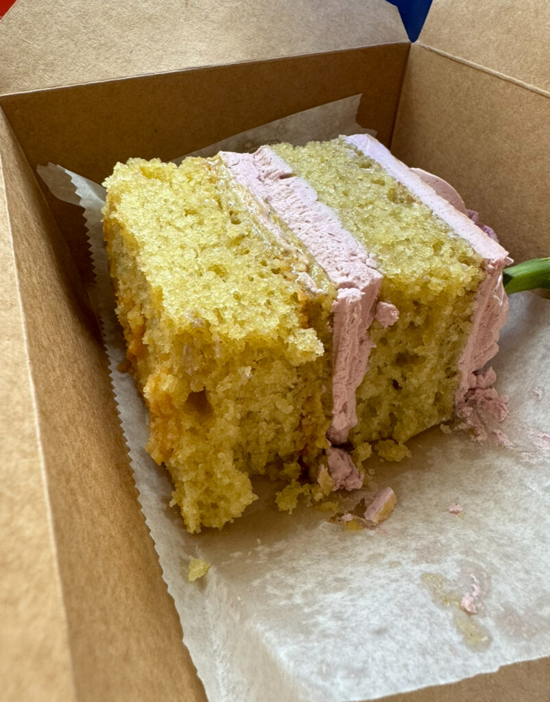 A slice of Capitol Jill\'s olive oil cake with whipped pistachio white chocolate ganache and blackberry preserve buttercream.