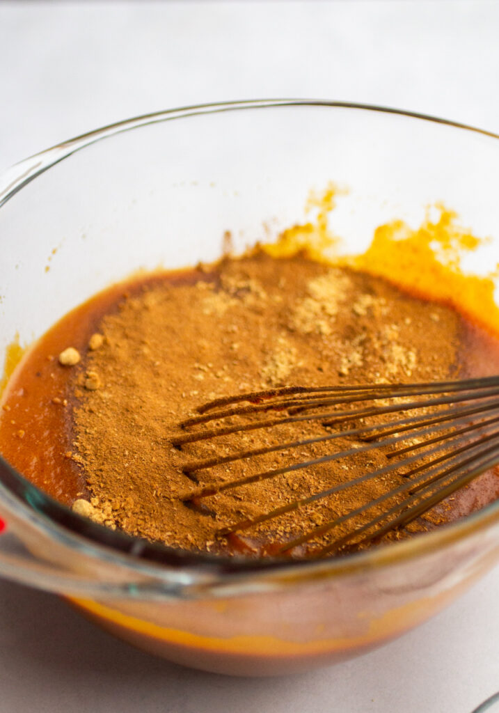 spices being mixed into the wet ingredients in a mixing bowl.
