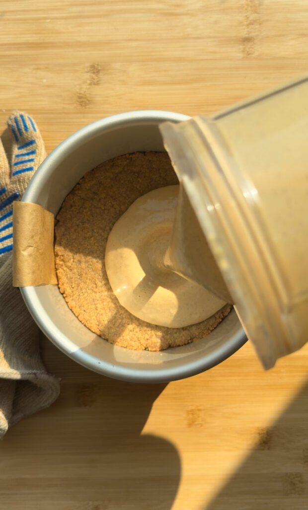 Pouring cheesecake mixture onto a graham crust.
