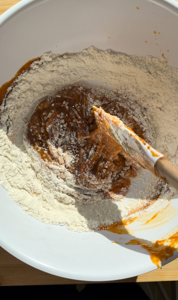 Stirring dry ingredients into the pumpkin mixture.