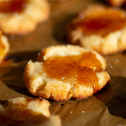 A cheesy jam thumbprint cookie on a cookie sheet.
