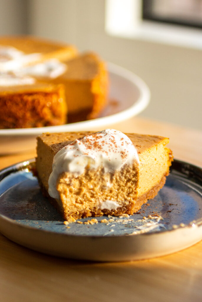 A slice of pumpkin cheesecake with a bite taken out of it.