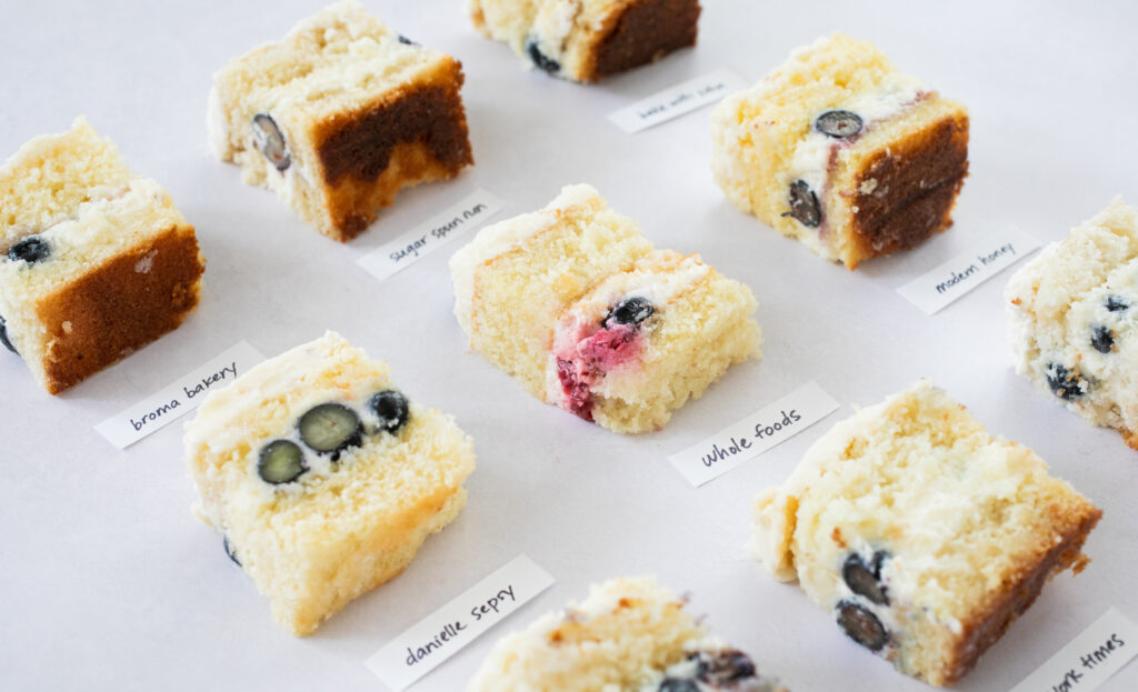 An angled shot of 9 squares of berry chantilly cake on a gray background.