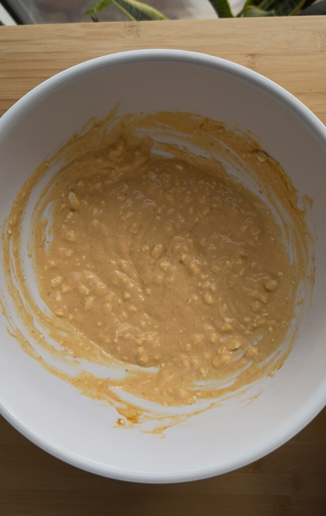 A white mixing bowl with a runny orange pancake batter.