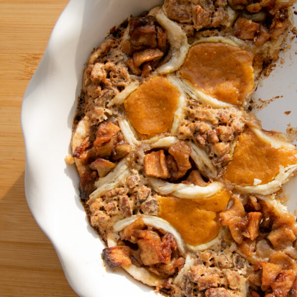 A white pie plate filled with pumpkin, pecan and apple mini hand pies.