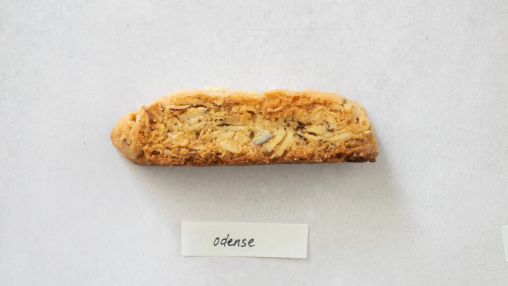 A pice of biscotti on a gray background with the label "Odense."