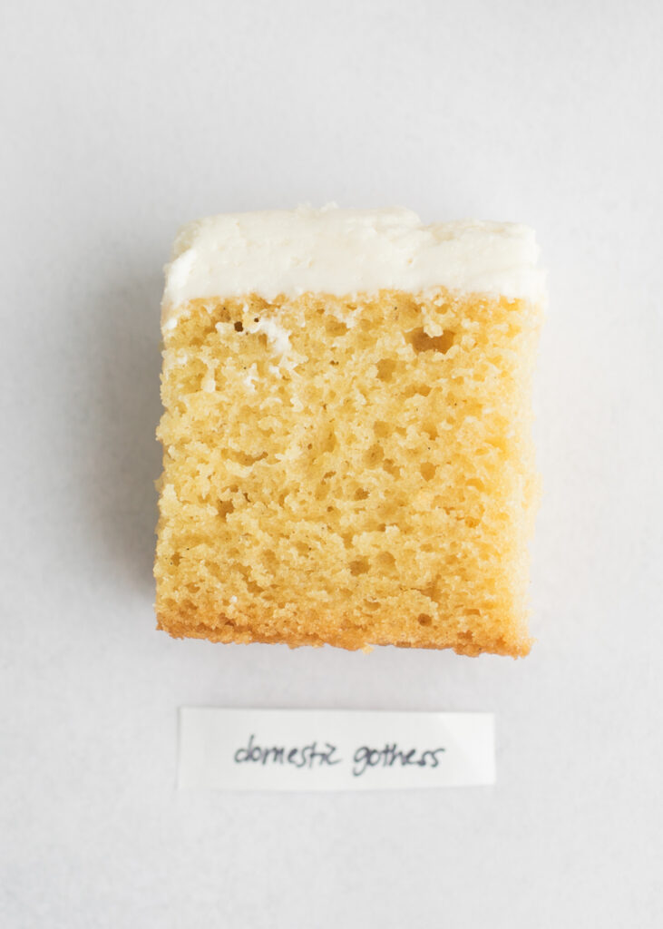 A slice of vegan vanilla cake with a label that says "Domestic Gothess."