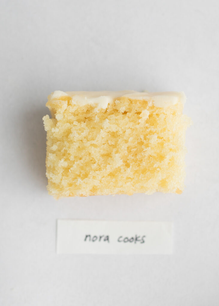 A slice of vegan vanilla cake with a label that says "Nora Cooks."