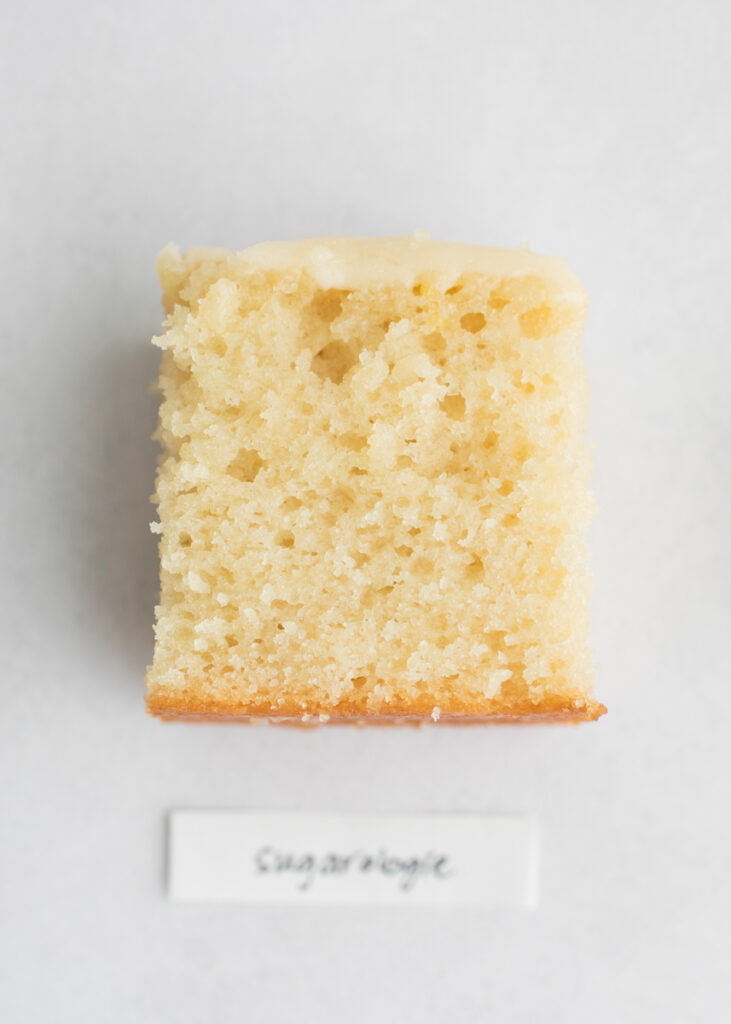 A slice of vegan vanilla cake with a label that says "Sugarologie."
