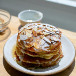 A stack of almond croissants on a white plate.