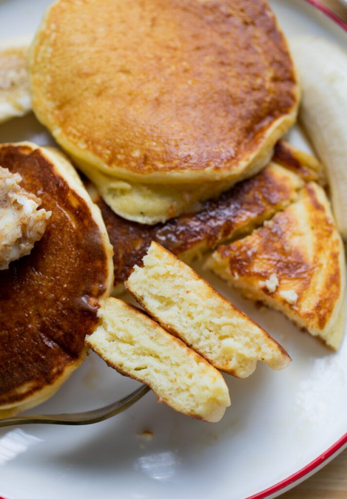 A fork holding a bite of pancake to reveal the fluffy interior.