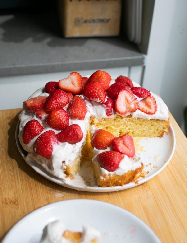 A cornmeal cake topped with a Greek yogurt frosting and cut strawberries.