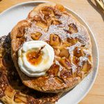 Two large apple pancakes on a white plate topped with a dollop of yogurt.